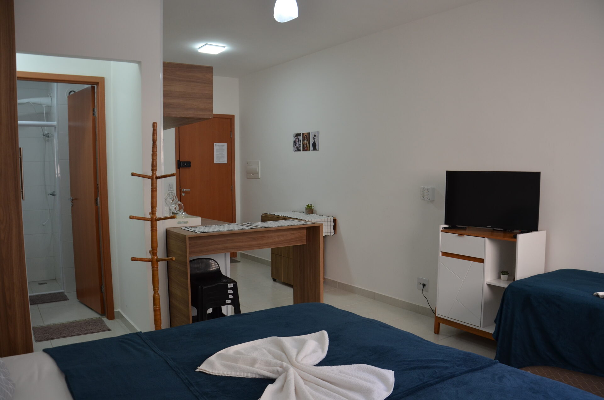 Apartamento 313 com televisão, mesa e camas arrumadas — Kadosch Empreendimentos, Cachoeira Paulista/SP, perto da Canção Nova
